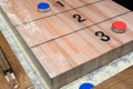 Vintage shuffle board game with red and blue disc on wooden shuffle table. Royalty Free Stock Photo