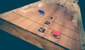 Vintage shuffle board game with red and blue disc on wooden shuffle table.