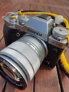 Vintage silver and black Fujifilm camera with brown leather strap on wooden table. Copy space for text. Antique, photography