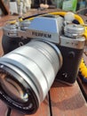 Vintage silver and black Fujifilm camera with brown leather strap on wooden table. Copy space for text. Antique, photography