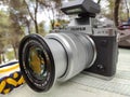 Vintage silver and black Fujifilm camera with brown leather strap on wooden table. Copy space for text