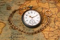 Vintage silver watch with gold chain lying on an old paper map. Round gray vintage clock with golden hands on yellow Royalty Free Stock Photo