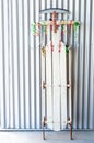 Vintage sled decorated with red, gold and green Christmas curling ribbon, leaning against a wall