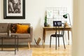 Vintage sofa next to a simple desk and chair in a living room interior. Real photo Royalty Free Stock Photo