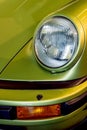 Vintage sports car headlight. Lime green motor vehicle close-up