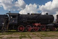 Vintage steam engine train under sunny blue sky with clouds