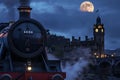 Vintage steam train with clock tower and full moon at night. Royalty Free Stock Photo