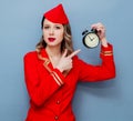Vintage stewardess wearing in red uniform with alarm clock