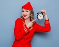 Vintage stewardess wearing in red uniform with alarm clock