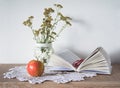 Vintage still life with book, glasses, apple and vase with flowers on doily Royalty Free Stock Photo