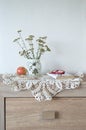 Vintage still life with a book, glasses, apple and vase with flowers on doily