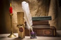 Vintage still life with glasses on old books near inkstand, feather, old paper and burning candle on canvas background Royalty Free Stock Photo