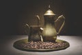 Vintage still life with heap of coffee beans near old copper coffeepots on bronze tray against canvas background