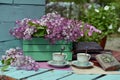 Vintage still life with open book or diary with lilac flowers bouquet and cups of tea in the garden. Royalty Free Stock Photo