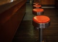 Vintage stools in the restaurant. Row vintage stools in front of wooden counter inside a vintage style bar Royalty Free Stock Photo