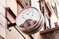 Vintage street clock with roman numerals hanging on the wall of building in center of european city. Outdoor analog Royalty Free Stock Photo