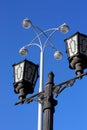 Vintage street lamp and modern lantern against a blue sky Royalty Free Stock Photo