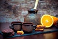 Vintage style ceramic cups, coffee brewing pot, fresh orange and chocolate cookies and candies