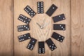 Vintage style clock made of domino plates on wooden background. Domino clock