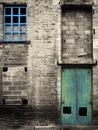 Vintage style colorized image of an abandoned industrial warehouse and factory building with blue windows and green door Royalty Free Stock Photo