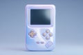 Retro handheld gaming device in pastel colors on a soft blue background Royalty Free Stock Photo