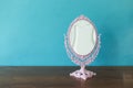 Vintage style makeup mirror on wooden table with space on blue wall backgroun Royalty Free Stock Photo