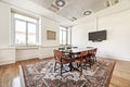 Vintage style office with rectangular wooden meeting table with wooden chairs upholstered in brown leather on a brown carpet and