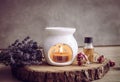 Vintage style picture of white ceramic candle aroma oil lamp with essential oil bottle and dry flower petals on natural pine wood Royalty Free Stock Photo