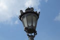 Vintage style street lamp top isolated on blue sky with clouds. Retro european lantern