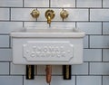 Vintage style victorian designed bathroom sink with porcelain basin and shiny brass taps and copper plumbing on a white tiled