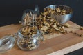 Vintage styled photo of sliced, chopped and dried various mushrooms in preserving glass and silver bowl standing on wooden desk o