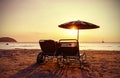 Vintage stylized beach chairs and umbrella at sunset.