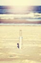 Vintage stylized message in a bottle on beach, shallow depth of Royalty Free Stock Photo