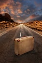 Vintage suitcase on road through desert