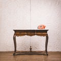 Vintage table with telephone against wall Royalty Free Stock Photo