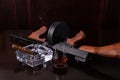 Vintage Thompson submachine gun on a dark brown table with a cigar and whiskey