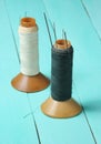 Vintage thread reels with needles on a blue wooden table. Royalty Free Stock Photo