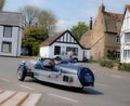 Vintage three-wheeled car seen taking a corner at speed.