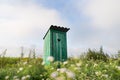 Vintage toilet. An outdoor rustic green toilet with a heart cut out on the door. Toilet in a field of flowers Royalty Free Stock Photo