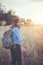 Vintage tone images of beautiful young hipster woman with backpack walking on meadow. Portrait of hiker girl outdoor. Royalty Free Stock Photo