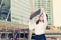 Vintage toned image of attractive business woman raises office document folder to shield from sunlight at street city. Royalty Free Stock Photo