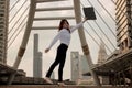 Vintage toned image of cheerful young Asian business woman raising her arms with ring binder at urban building background. Royalty Free Stock Photo