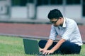 Vintage toned image of relaxed young Asian business man working with laptop on green grass. Royalty Free Stock Photo