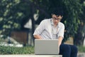 Vintage toned image of relaxed young Asian business man working with laptop at public park. Royalty Free Stock Photo