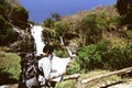 Vintage toned image of young backpacker exploring map on his hands in waterfall national park background.