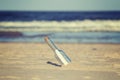 Vintage toned message in a bottle on beach. Royalty Free Stock Photo