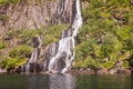 Majestic waterfall in Trollfjorden, Lofoten, with sun-kissed cliffs and greenery Royalty Free Stock Photo