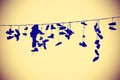 Vintage toned silhouettes of shoes hanging on cable. Royalty Free Stock Photo