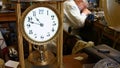 Vintage torsion pendulum clock on table while horologist working in background