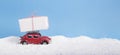 Vintage toy car Volkswagen Beetle with gift box on the roof driving over snow drifts